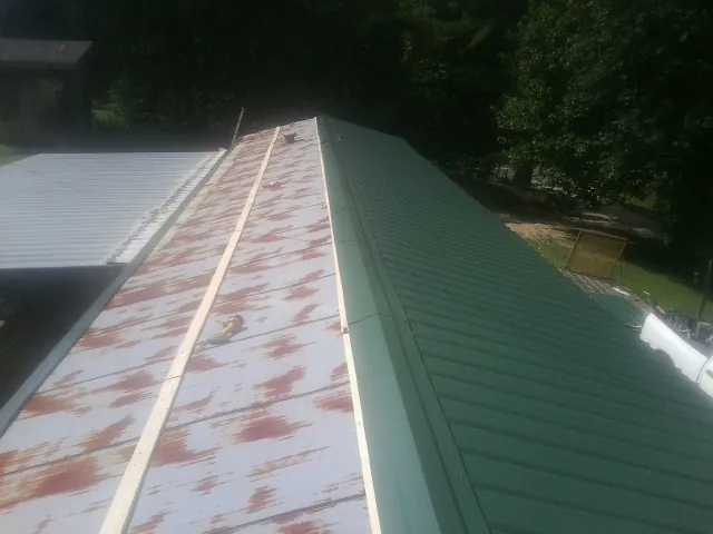 Old rusted panels beside newly installed green metal roofing — Wind Damage Roof Repair by Roofing Brothers in Bridgeview
