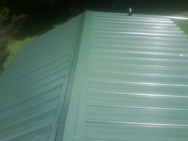 New green metal panels meeting at the ridge of a roof — Flat Roof Repair work by our crew in Bridgeview