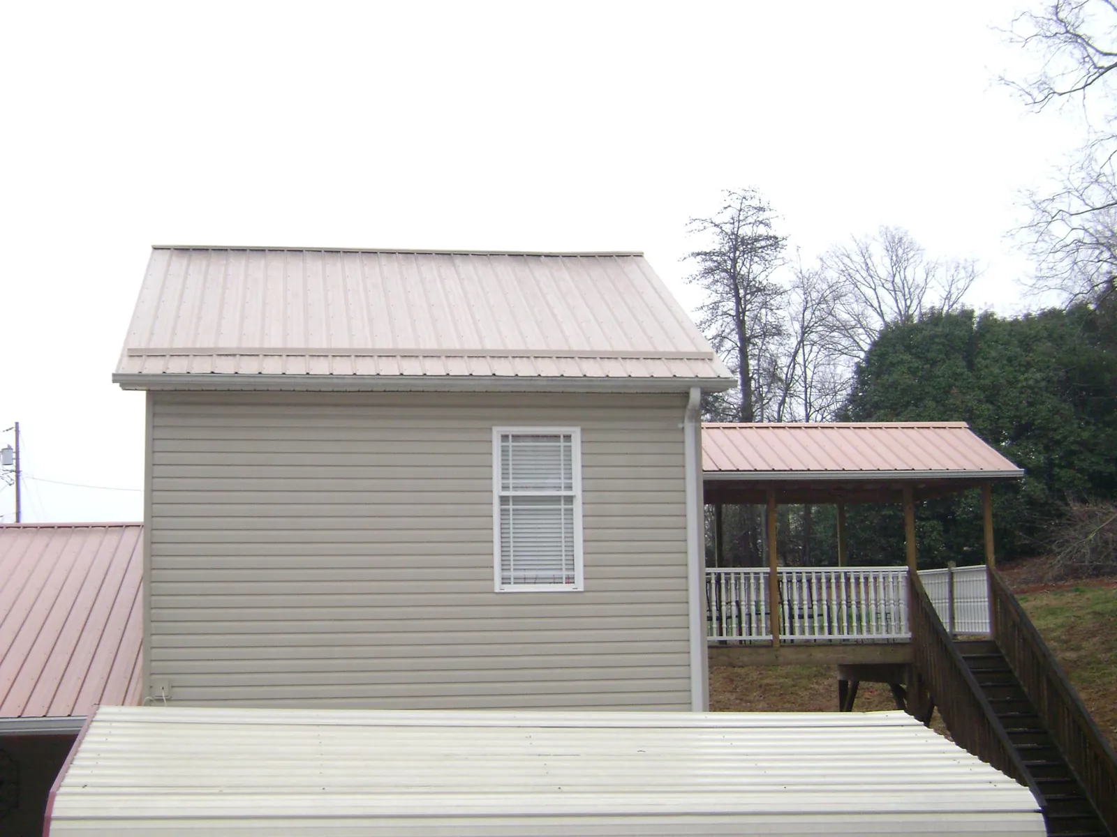 Tan metal roofs on a two story addition and attached porch, from a Roof Replacement job in Bridgeview